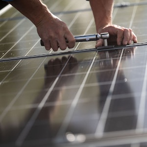 Ein Mitarbeiter montiert Photovoltaikmodule auf dem Dach eines Wohnhauses.