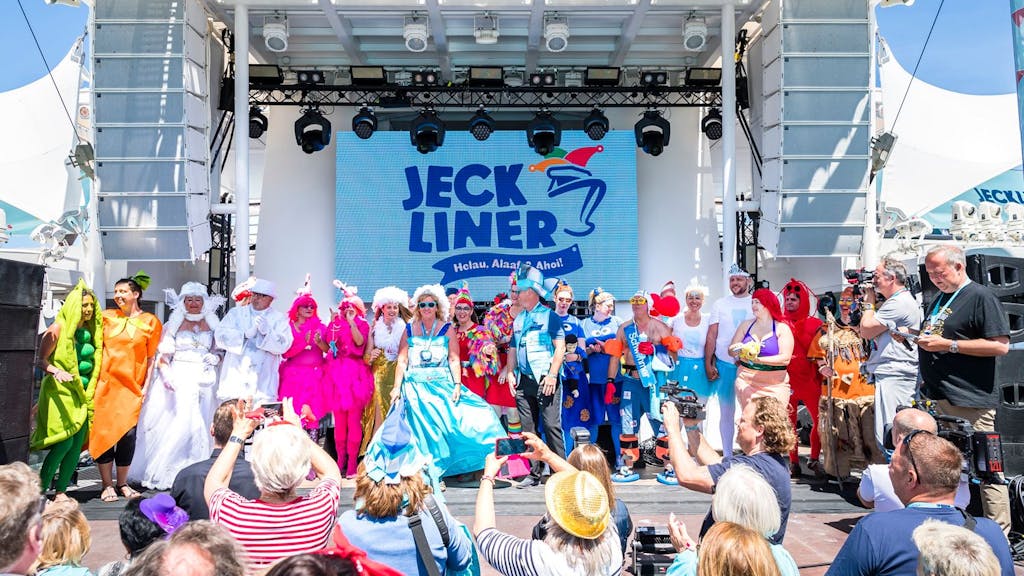 Das undatierte Foto zeigt verkleidete Karnevalistinnen und Karnevalisten, die auf und vor einer Bühne auf dem Kreuzfahrtschiff namens „Jeckliner“ feiern.
