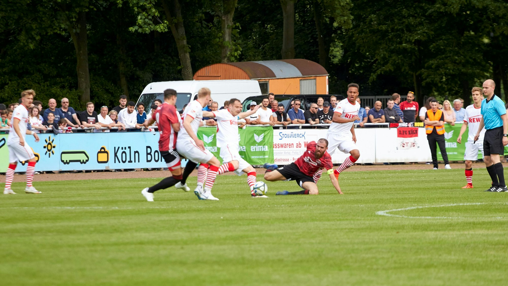Mehrere Fußballspieler konkurrieren während eines Spiels auf einem Rasenplatz um den Ball.