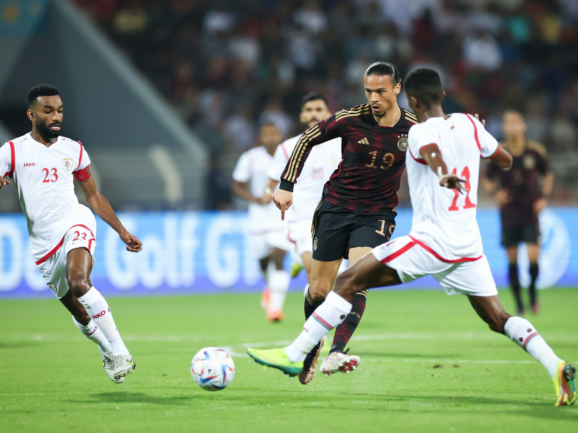 Deutschlands Leroy Sané (M) passt den Ball gegen Harib Al-Saadi (l) und Amjad al-Harthi (r).