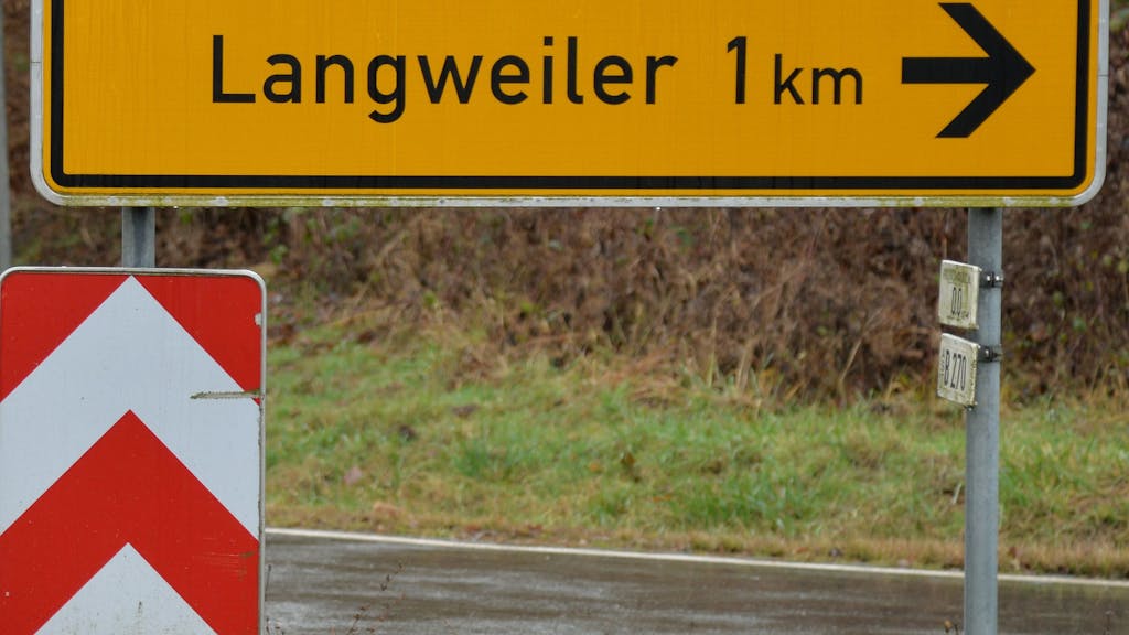 Ein Verkehrsschild zeigt den Weg in den Ort Langweiler (Kreis Kusel). 