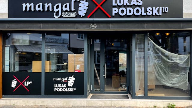 Über einem Ladenlokal ist ein Schild mit „mangal, Lukas Podolski“ angebracht, in den Innenräumen laufen noch Bauarbeiten.