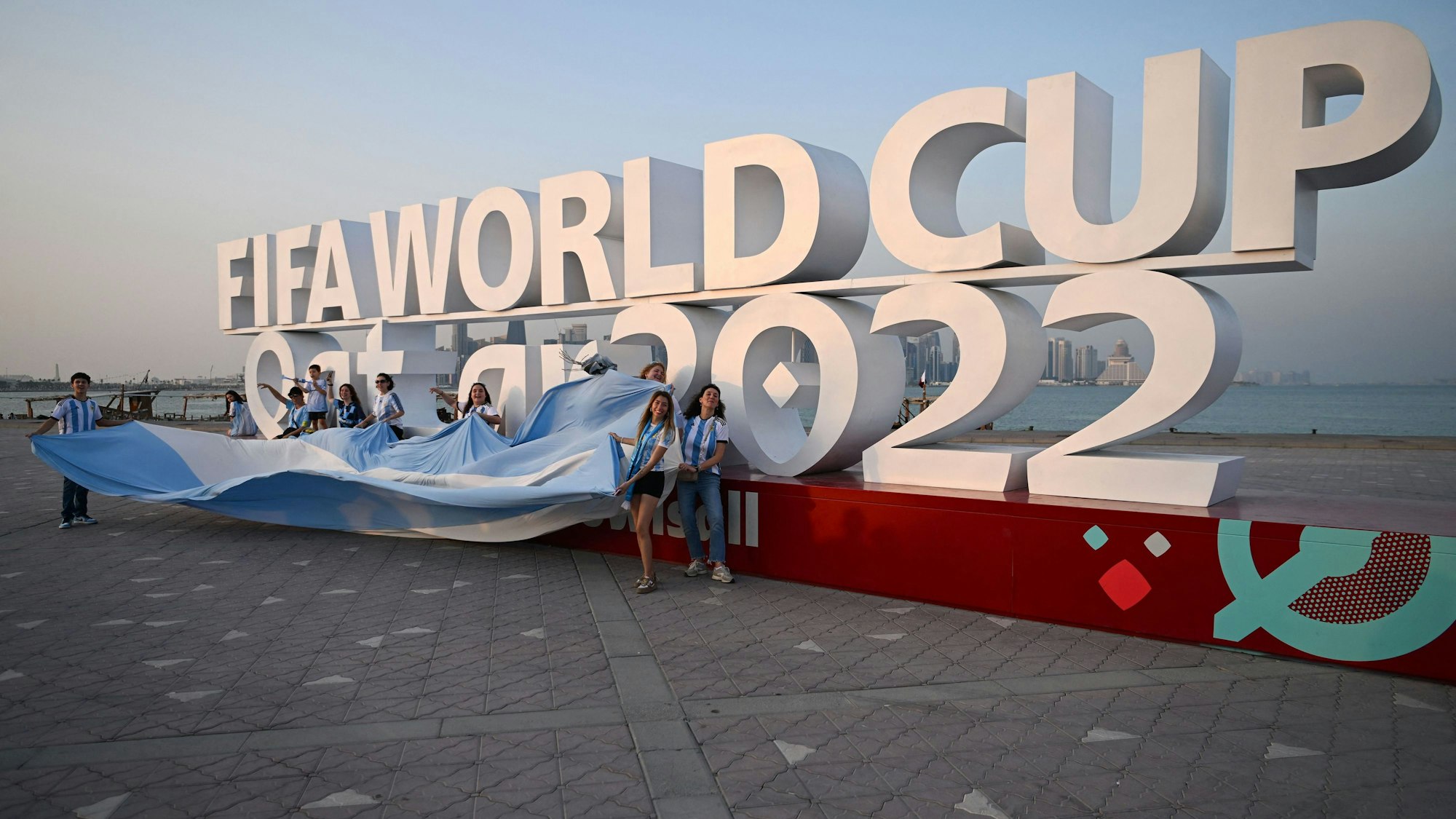 Fußballfans posieren am 7. November 2022 vor dem Logo der WM 2022 in Katar.