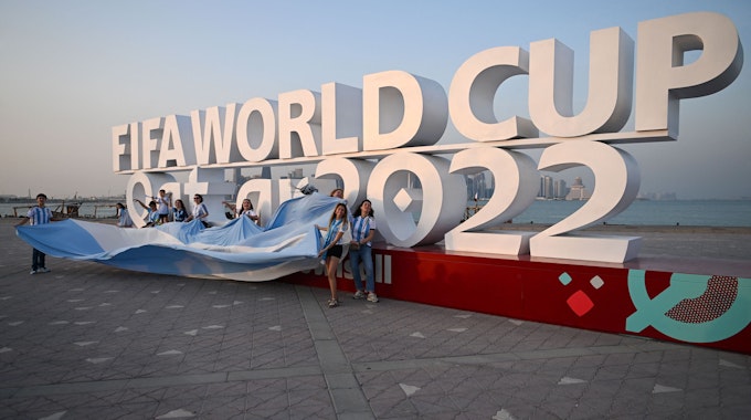 Fußballfans posieren am 7. November 2022 vor dem Logo der WM 2022 in Katar.