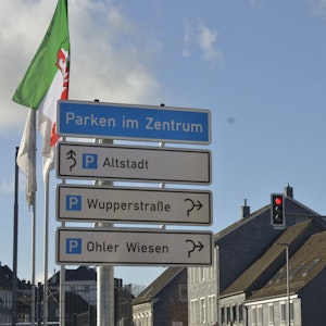 Das Parkleitsystem zeigt auf verschiedenen Schildern die Richtungen der Parkplätze in der Altstadt, der Wupperstraße und an den Ohler Wisen an. Im Hintergrund ist eine Kirche zu sehen.