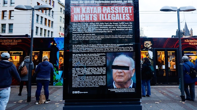 Plakat mit Foto und Aussagen von Uli Hoeneß am Neumarkt in Köln. Viele Menschen stehen drum herum.