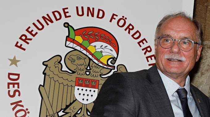 Bernhard Conin steht vor einem Plakat der Freunde und Förderer des Kölnischen Brauchtums.