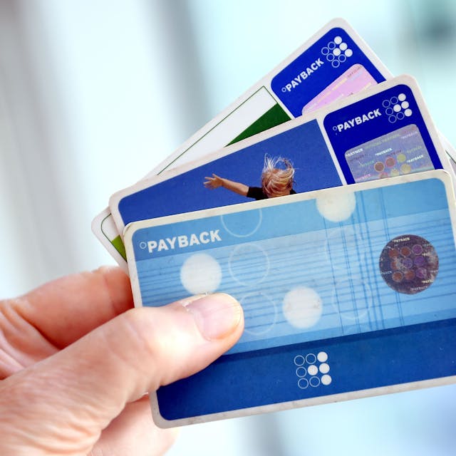 Eine Hand hält drei Payback-Karten wie einen Fächer.