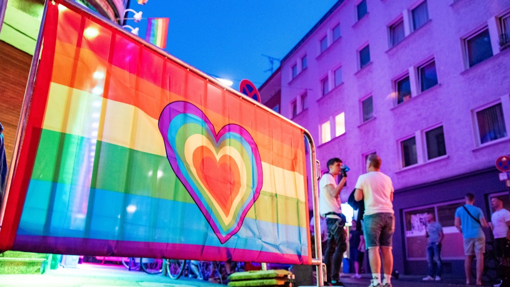 Eine Regenbogenfahne mit Herz schmückt einen Treffpunkt der Queer-Szene in Köln.