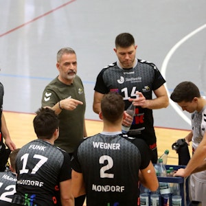 Cheftrainer Tasos Vlasakidis vom TuS Mondorf macht Ansagen und gestikuliert, seine Spieler hören gespannt zu.