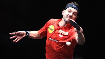 Tischtennis-Profi Timo Boll schlägt einen Ball, sein Körper und seine Gesichtszüge sind angespannt.