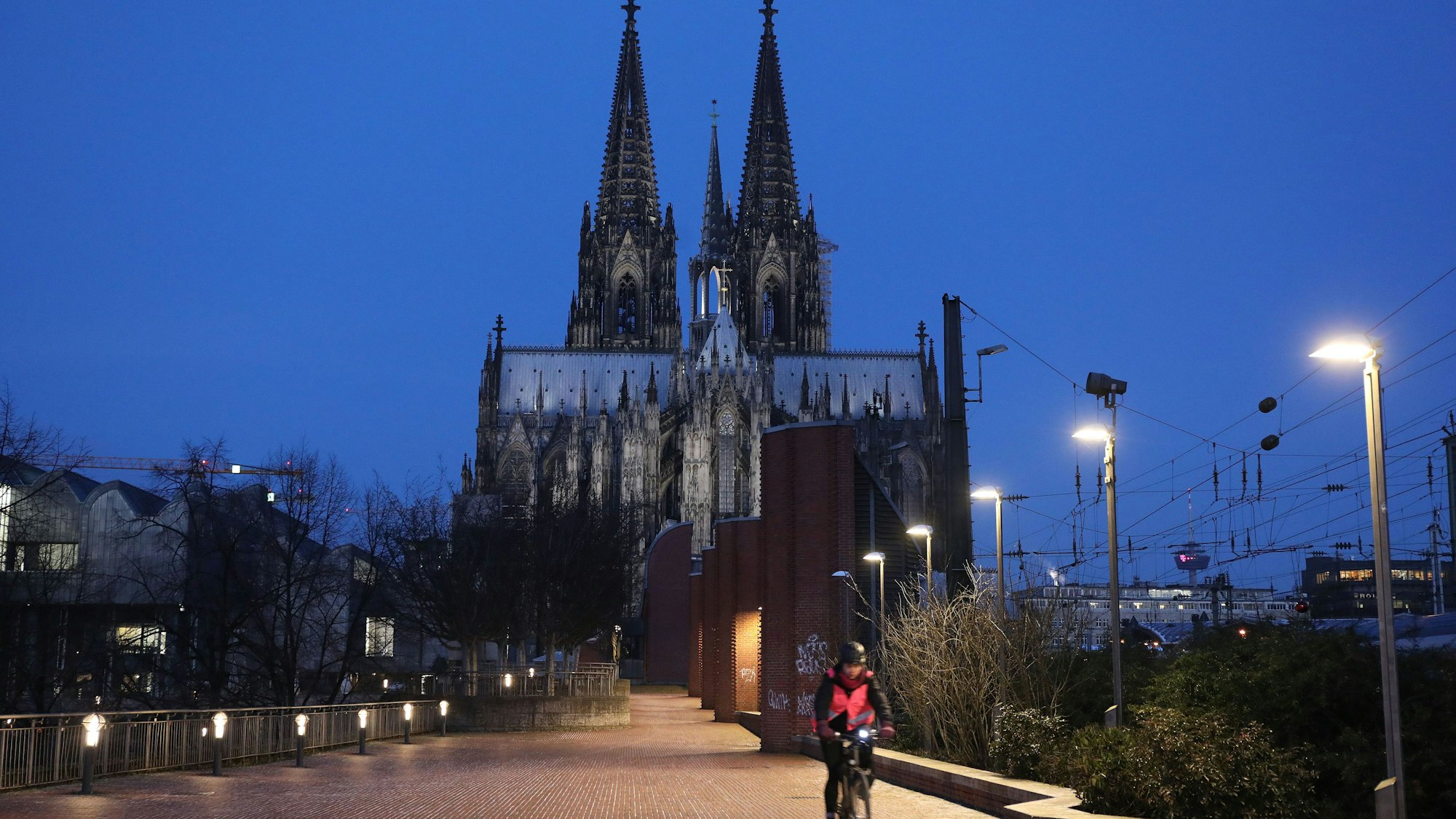 Ein Radfahrer fährt am Morgen am Kölner Dom vorbei.