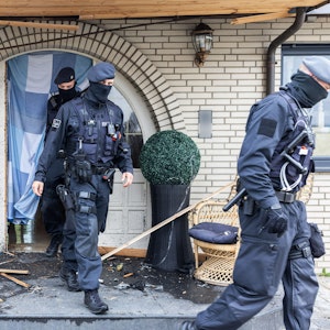 Polizisten verlassen in Leverkusen eine Villa durch eine zerstörte Eingangstür nach Durchsuchungen im Bereich der Clankriminalität.