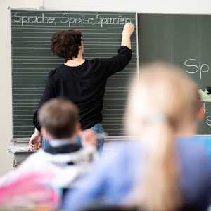 Eine Lehrerin schreibt in einer Grundschule Wörter mit «Sp» am Anfang an eine Tafel.