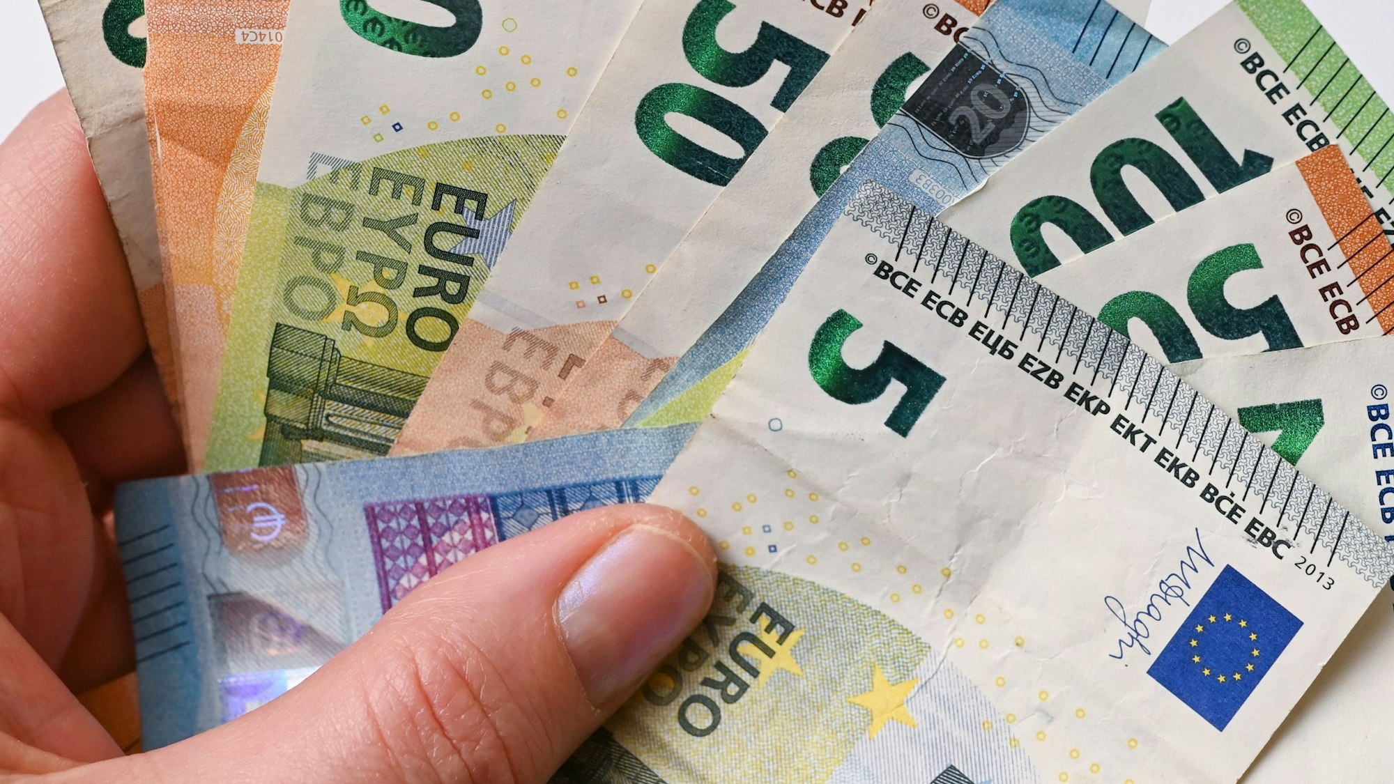 Eine Frau hält Eurobanknoten in ihren Händen (gestellte Aufnahme).