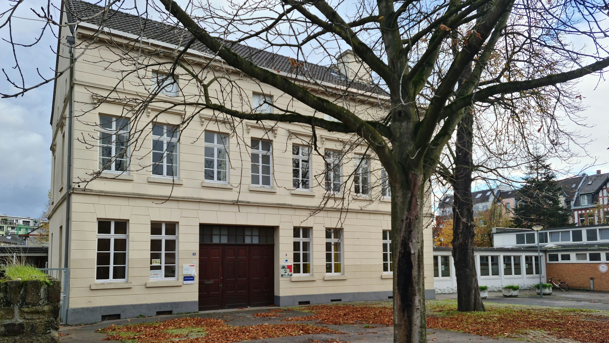Die Förderschule in Köln-Bickendorf ist ein „wirtschaftlicher Totalschaden“ und wird aufgegeben. Vorne im Bild ist ein kahler Baum, hinten die beigefarbene Schule in einem Altbau.