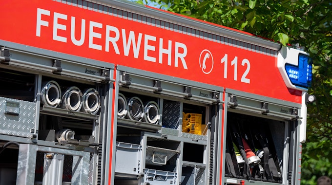Großaufnahme eines Feuerwehr-Autos. In weißen Lettern steht auf rotem Grund „Feuerwehr 112“. Es sind außerdem einige Schläuche und Gerätschaften zu sehen.