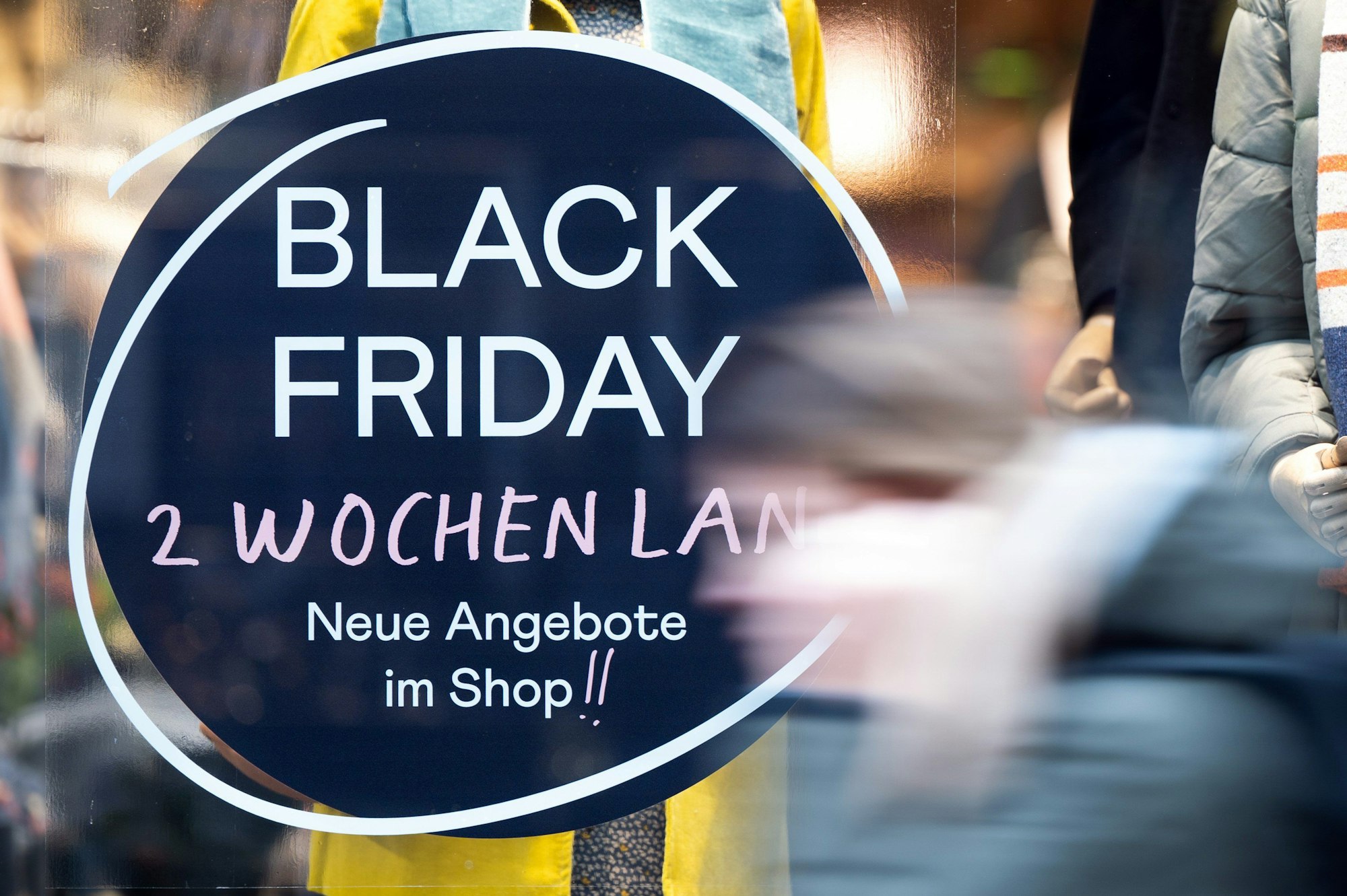 Eine Frau geht in Köln an einem Geschäft vorbei, das mit Black-Friday-Angeboten wirbt.