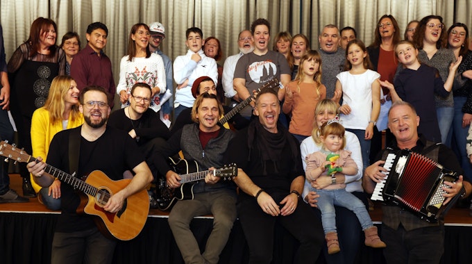 Der Familien-Workshop im Kölner Maritim-Hotel gehört zu den Höhepunkten der Jubiläumsausstellung „50 Jahre Höhner“ des Kölnischen Stadtmuseums. Menschen singen in drei Reihen sitzend und stehend auf einer Bühne.



