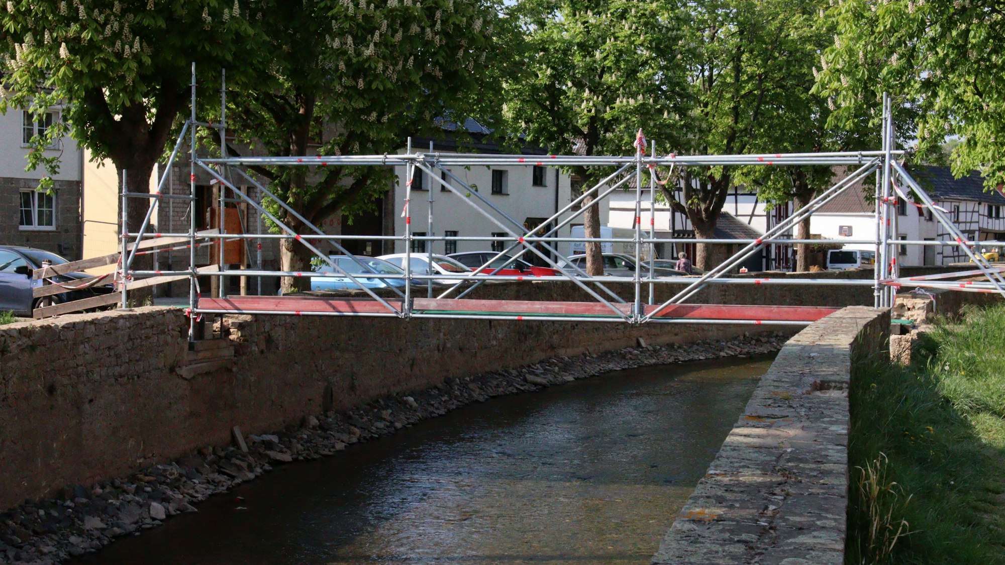 Das Foto zeigte eine provisorische Brücke an der Ley in Iversheim, über die die Erft in Richtung Kindergarten überquert werden kann. Dort früheren Erftbrücken in Iversheim wurden durch die Flut zerstört. Sie sollen in Kürze saniert werden.