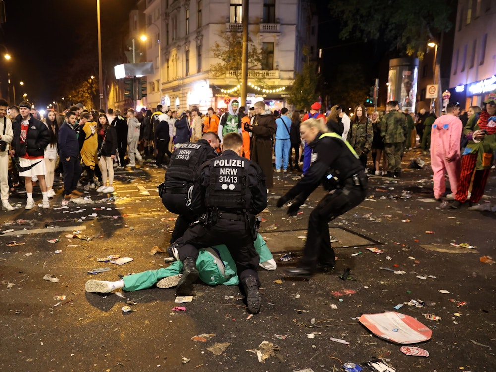 Polizisten fixieren einen Mann auf dem Boden während der Feierlichkeiten zum 11.11. in Köln.