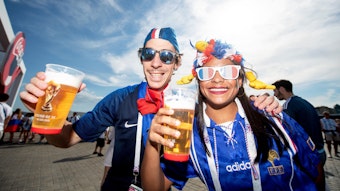 Fußball-Weltmeisterschaft 2018 in Russland: Eine Frau und ein Mann in Trikots der französischen Nationalmannschaft und mit Sonnenbrillen lachen in die Kamera, sie halten Plastikbecher mit Bier.