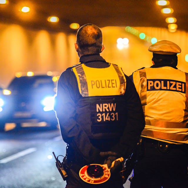 Zwei Polizisten stehen mit einer Kelle in einem Tunnel. Ein Auto kommt ihnen entgegen.&nbsp;
