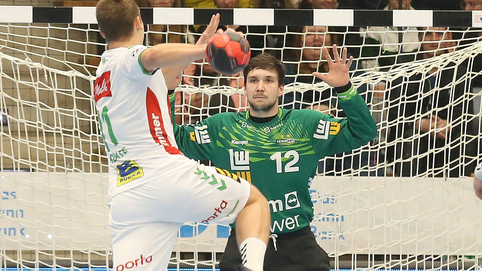 Ein Handballer wird einen Bal aufs Tor, in dem Daniel Rebmann mit grünem Trikot steht.