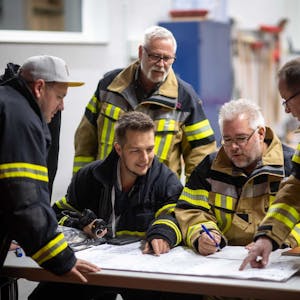Die Feuerwehrleute der Löschgruppe Dom-Esch sitzt über einem Schichtplan zusammen.&nbsp;