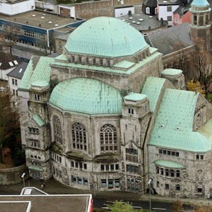 Die Alte Synagoge in Essen ist eine der größten freistehenden Synagogenbauten Europas. Auf dem Bild ist der aufwändige Bau von oben zu sehen, er steht an einer vierspurigen Straße, davor steht ein Polizeiwagen. Das Dach der Alten Synagoge ist mit Grünspan überzogen, die Mauern sind aus hellem Stein.