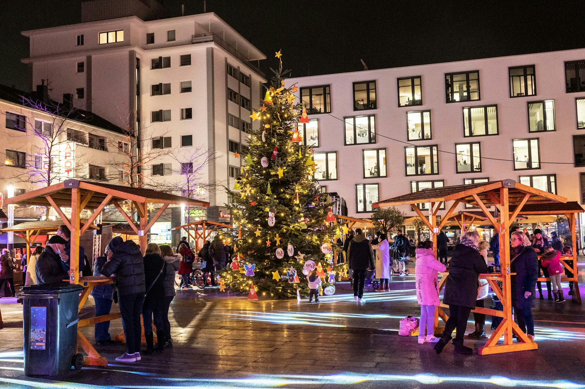 In der Mitte des Maternusplatzes steht ein Weihnachtsbaum. Besucher trinken Glühwein.