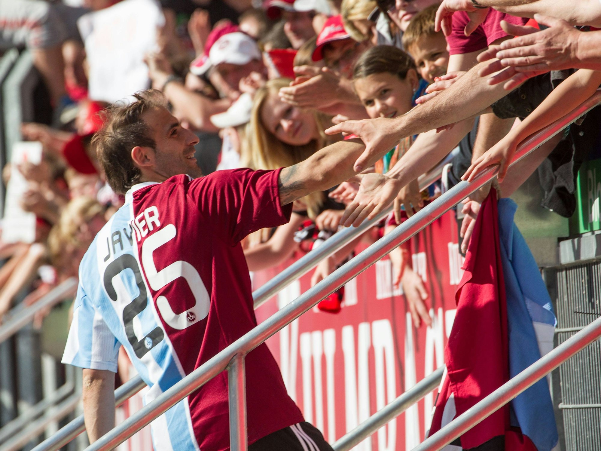 Javier Pinola klatscht mehrere Fans vom 1. FC Nürnberg an der Tribüne ab.
