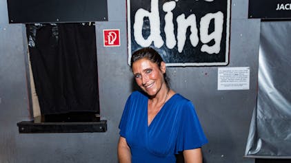 Claudia Wecker, im blauen Kleid, fotografiert im „Studentenclub Das Ding“, den sie betreibt.