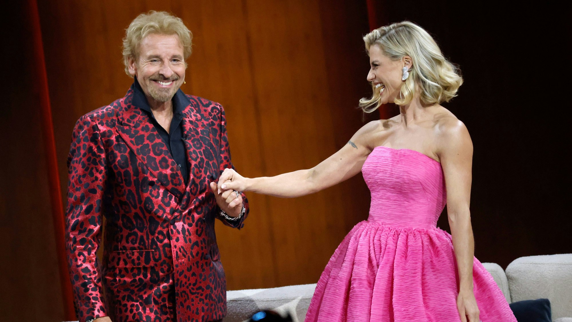 Thomas Gottschalk im roten Leoprint-Anzug und Michelle Hunziker in einem pinken Kleid stehen in der Messehalle in Friedrichshafen während der "Wetten, dass..?"-Sendung