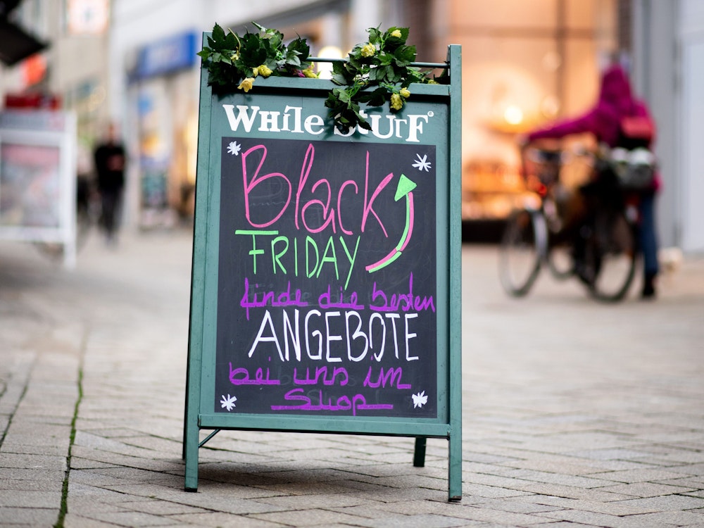 Ein Schild mit der Aufschrift „Black Friday Angebote“ steht vor einem Geschäft.