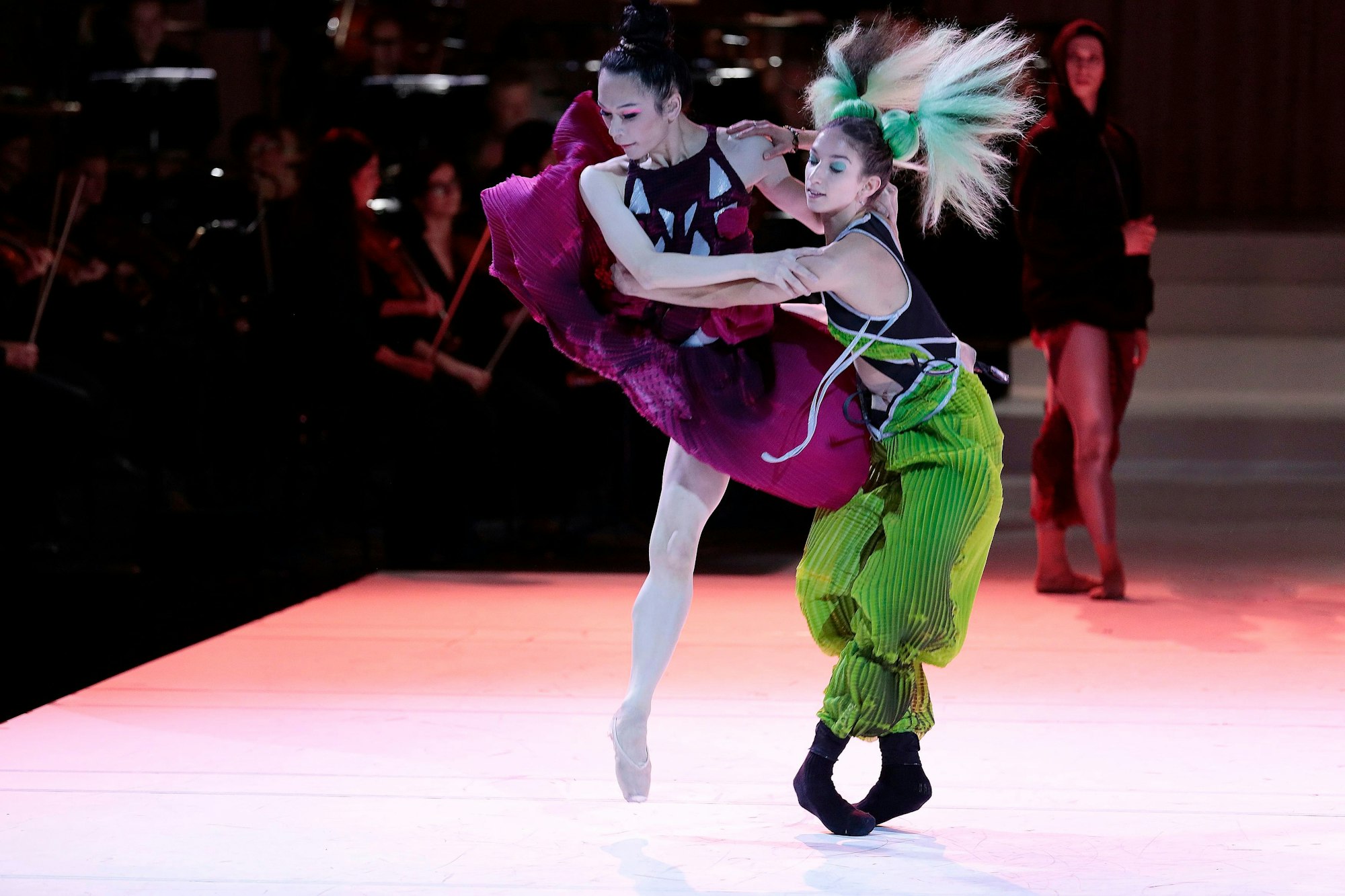 Zwei Tänzer in bunten Kostümen drehen sich auf der Bühne der Kölner „Petruschka“-Aufführung.