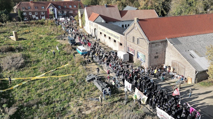 Lützerath von oben gesehen: Bei einer Demonstration in Lützerath ziehen mehrere Hundert Teilnehmer mit Banner durch das Dorf.&nbsp;