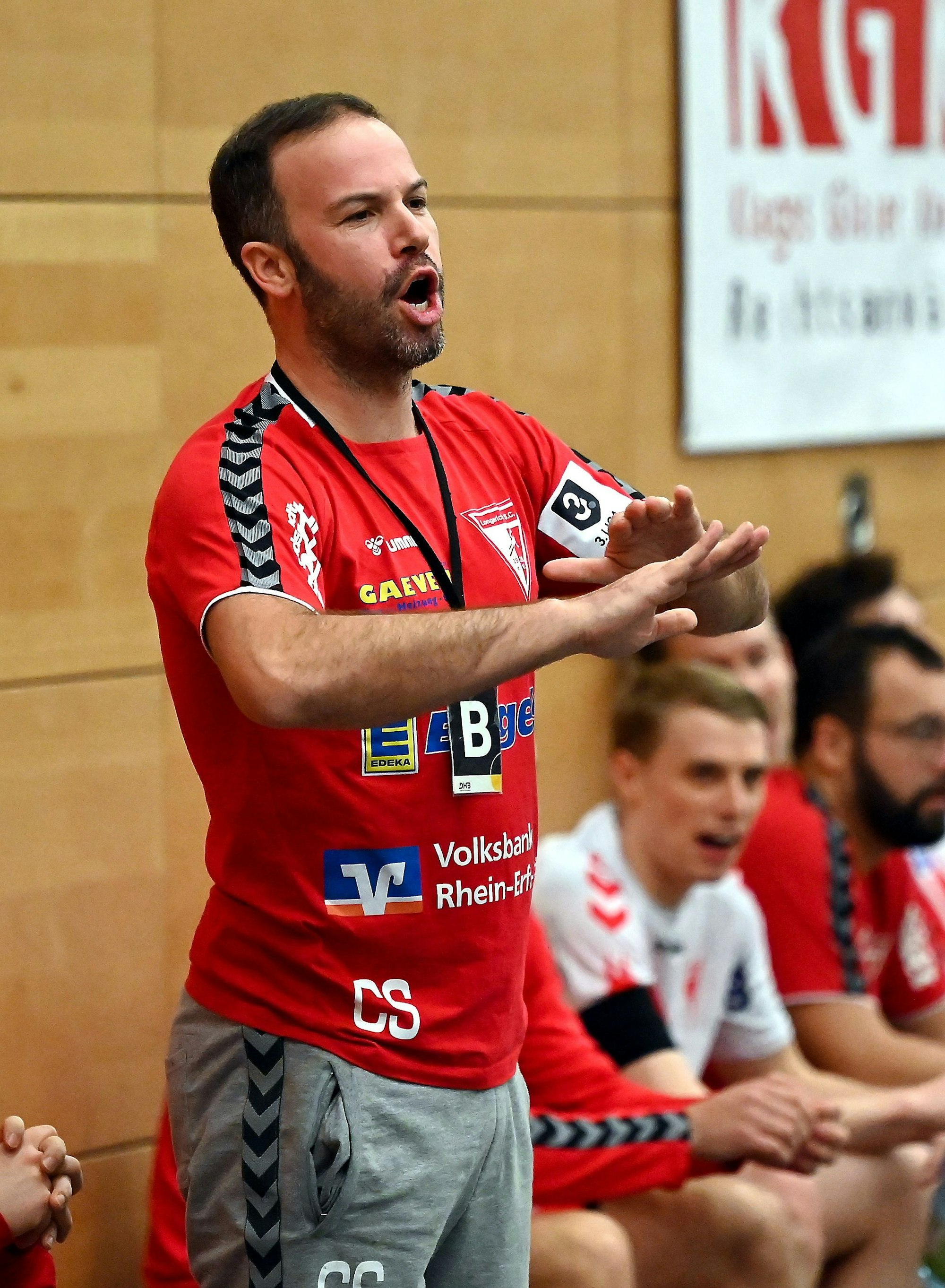 Ein Handballtrainer steht am Spielfeldrand und gestikuliert.