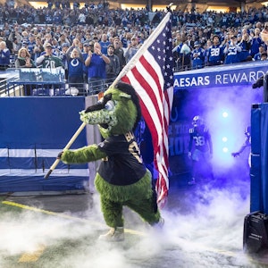 NFL-Maskottchen Blue läuft mit einer USA-Flagge auf den Rasen.