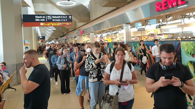 Menschen warten in einer sehr langen Schlange am Flughafen Köln/Bonn für den Check-in und die Sicherheitskontrolle.&nbsp;