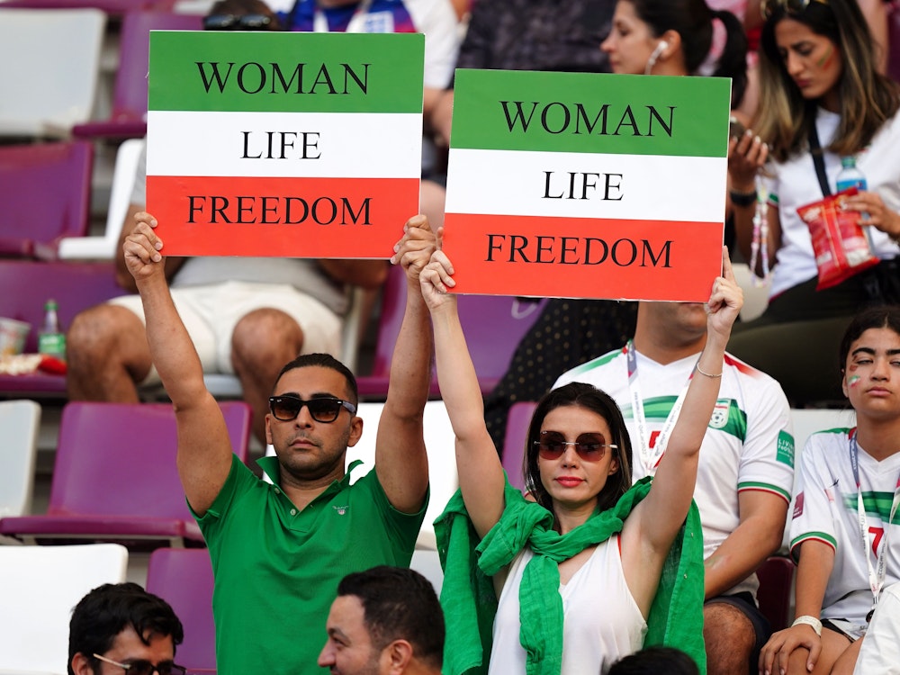 Iranische Fans auf der Tribüne halten vor dem Spiel Schilder mit der Aufschrift "Woman Life Freedom" hoch.
