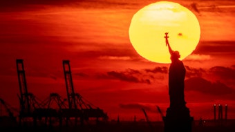 Die Sonne geht hinter der Freiheitsstatue in New York unter.