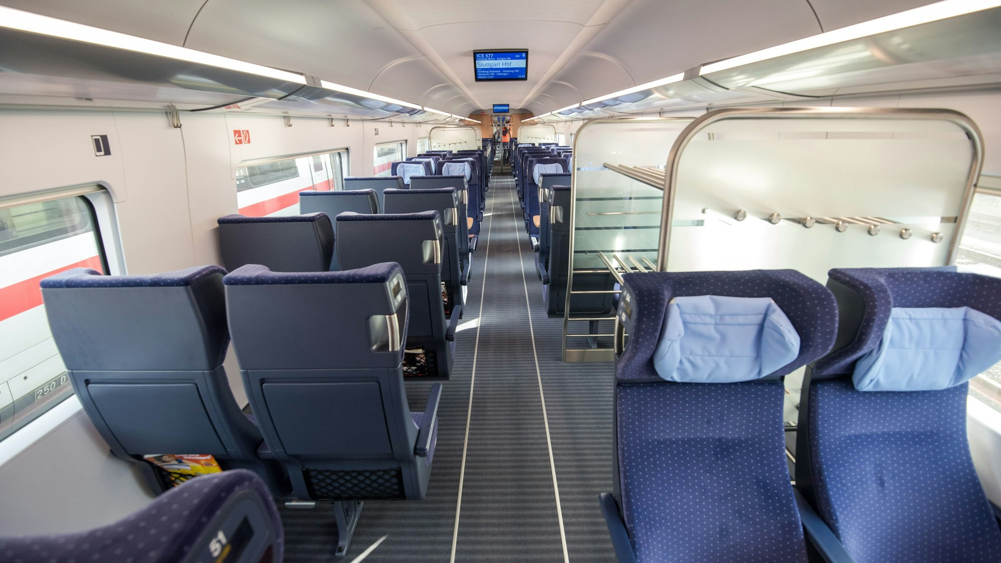 Ein ICE der Deutschen Bahn. Zu sehen sind mehrere blaue Sitze und eine Kofferablage in einem leeren Abteil.