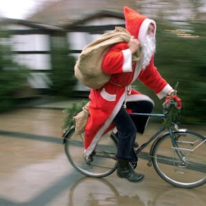 Mit rasantem Tempo fährt ein als Nikolaus verkleideter Mann auf seinem Fahrrad durch eine Fußgängerzone.