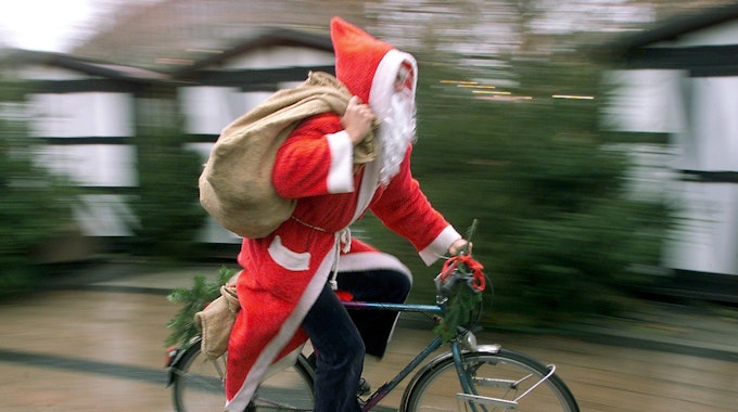 Mit rasantem Tempo fährt ein als Nikolaus verkleideter Mann auf seinem Fahrrad durch eine Fußgängerzone.