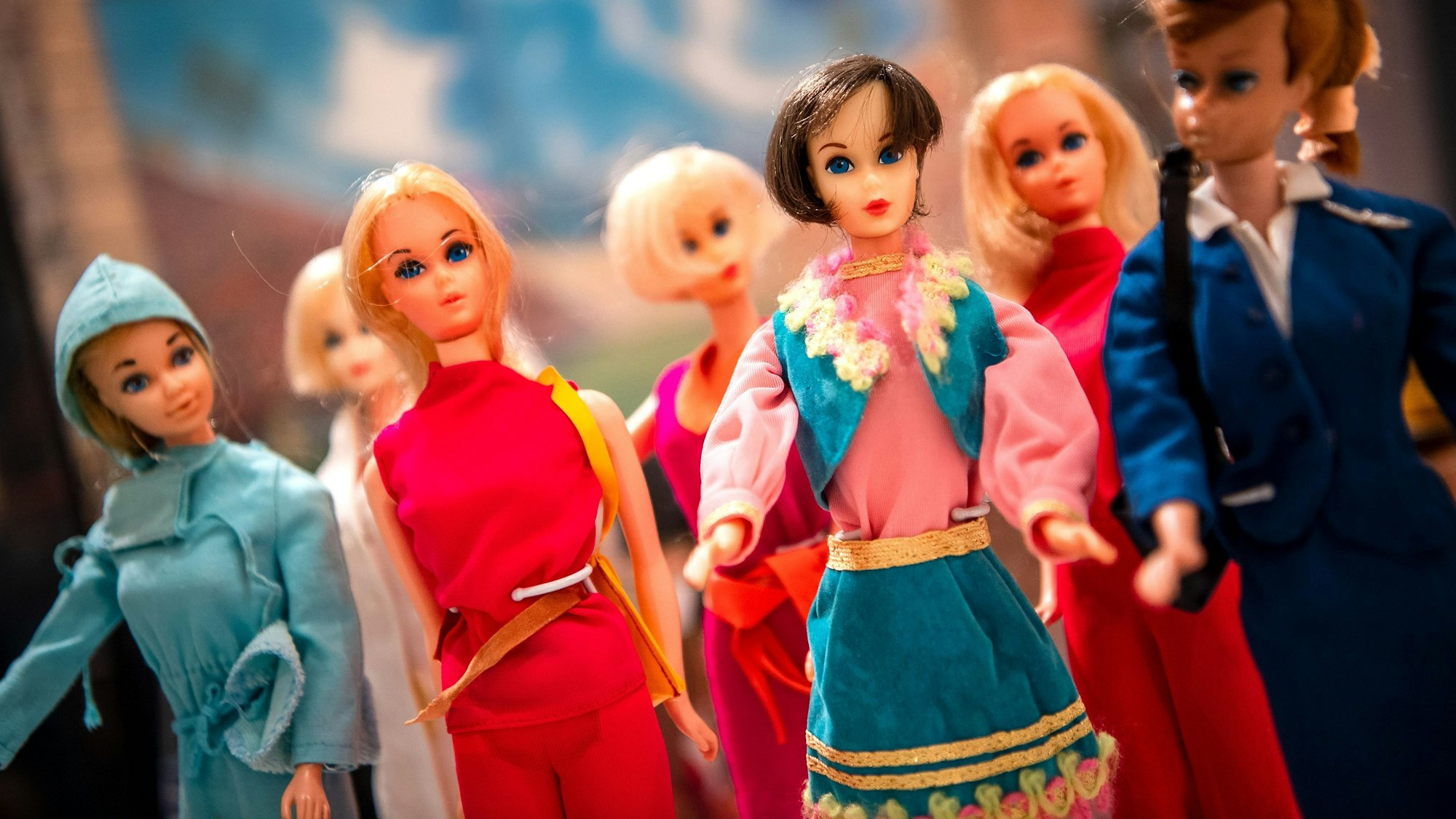 Verschiedene Barbie-Puppen stehen in einer Ausstellung nebeneinander