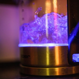 Von einer eingebauten Lampe blau beleuchtet ist kochendes Teewasser in einem Wasserkocher.