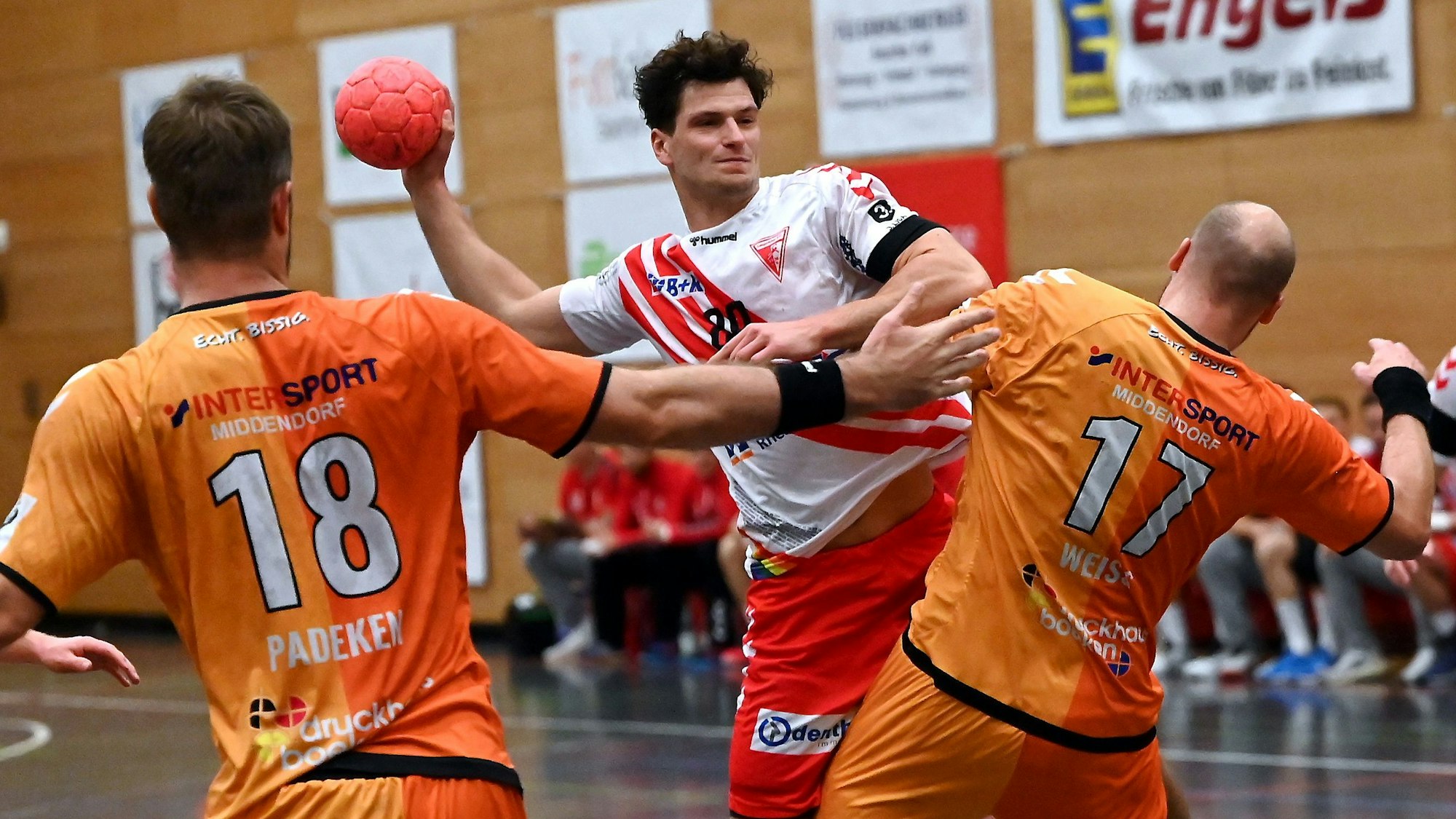Ein Handballer setzt gegen zwei Gegner zum Wurf an.