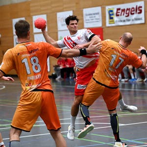 Ein Handballer setzt gegen zwei Gegner zum Wurf an.&nbsp;