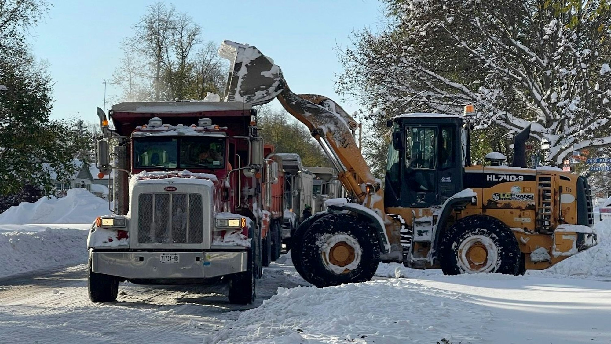 Schneeräumung mit Bagger und Trucks auf der Straße in Buffalo, New York.